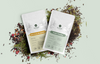 Two terazi tea packages surrounded by loose tea leaves on a light green background